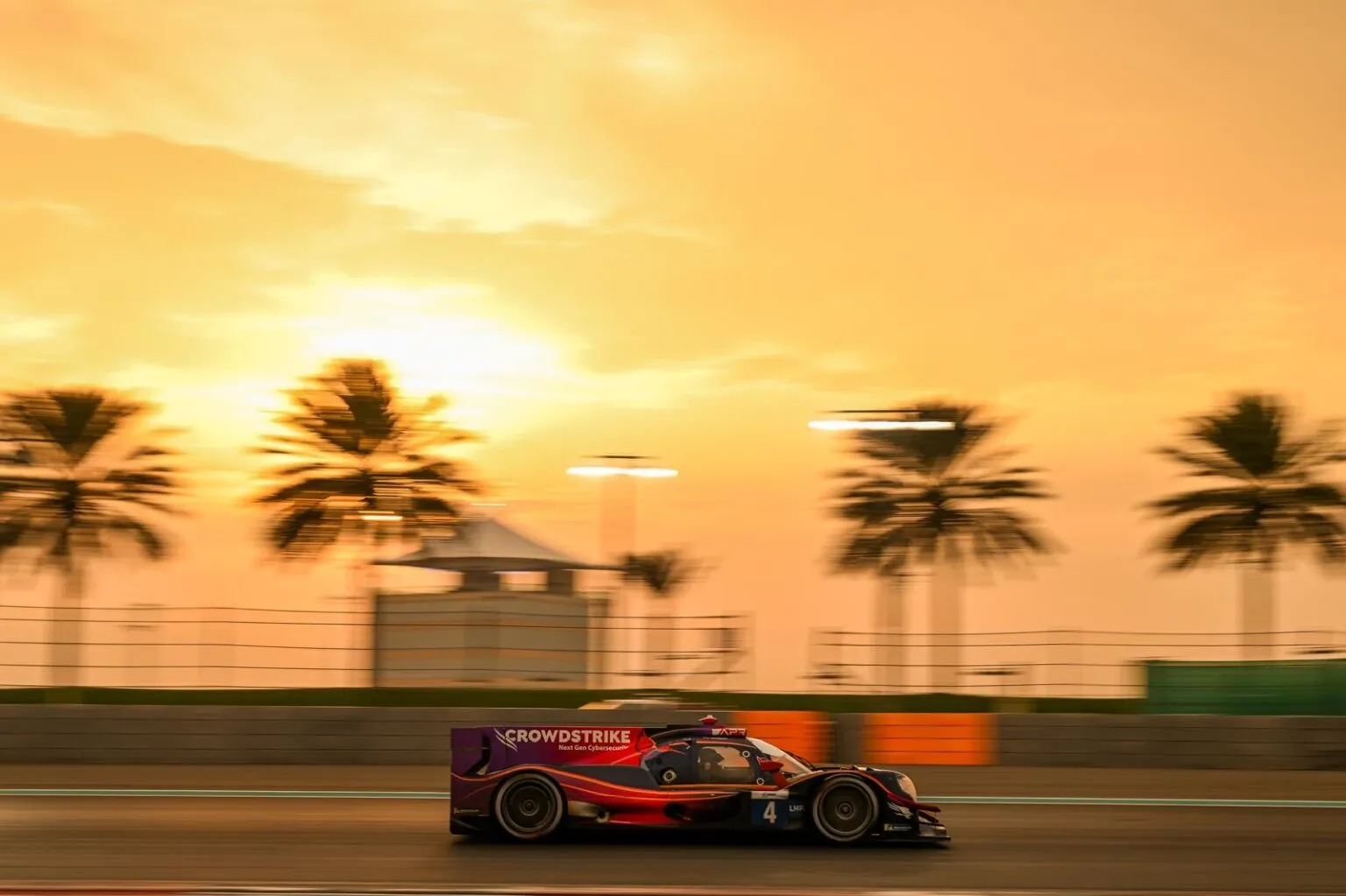 Auto de carreras con la marca CrowdStrike en la pista al atardecer