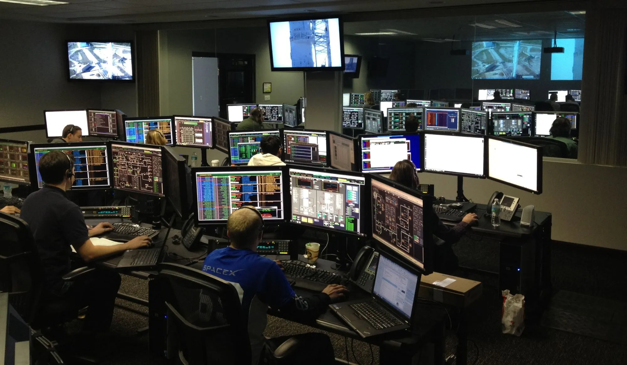 Operadores trabajando frente a múltiples monitores en una sala de control